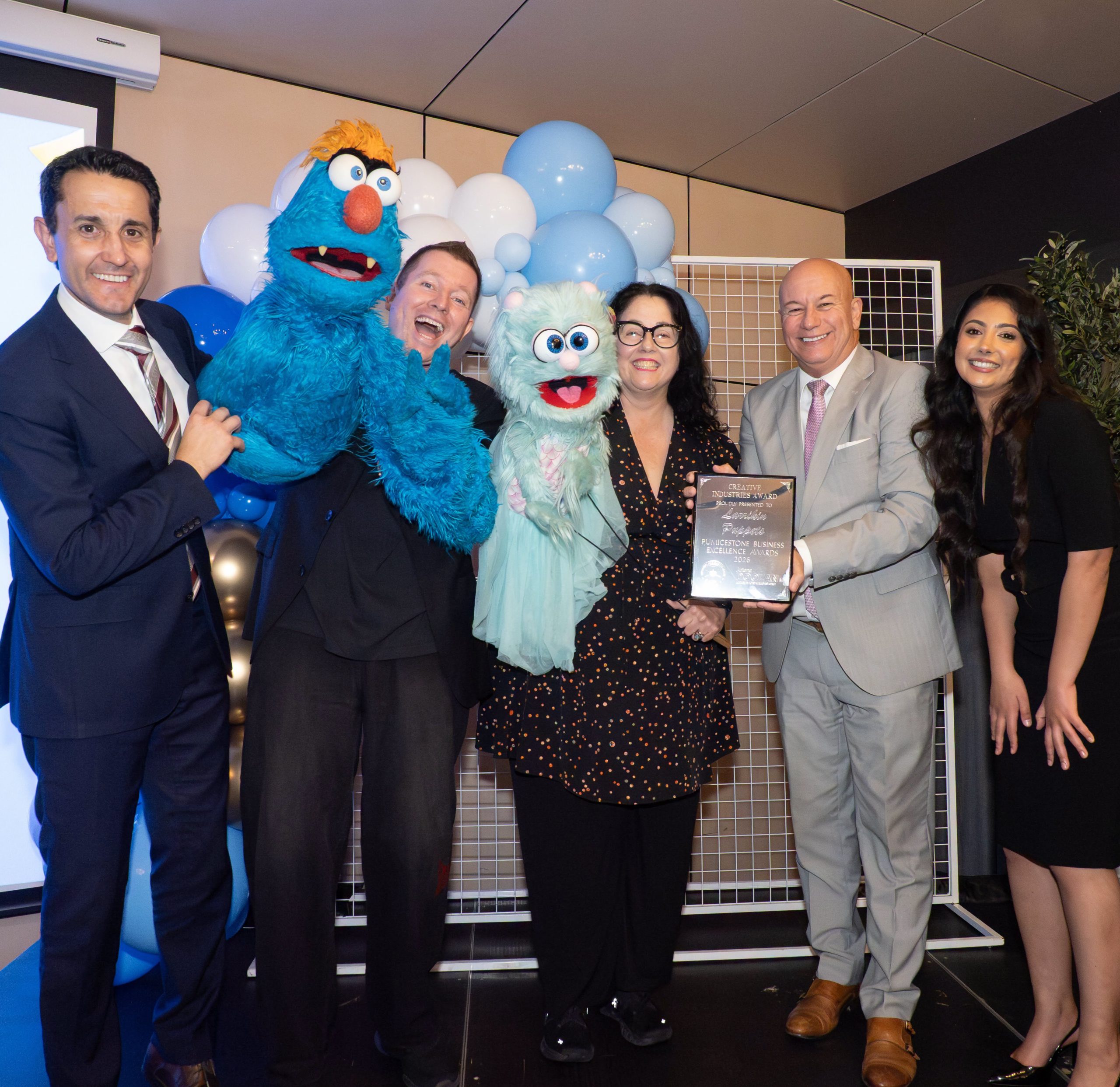 Brett Hansen and Elissa Jenkins of Larrikin Puppets with puppet characters Troggg and Marina after winning the Creative Industries Award at the 2026 Pumicestone Business Excellence Awards.
